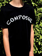 Load image into Gallery viewer, Black T-shirt with white handchalked effect writing of "Composer" in white. Shown on Model side view.