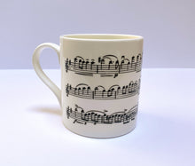 Load image into Gallery viewer, Music gift ideal for classical music fans. Elegant bone china mug with a section of Mendelssohn's Violin Concerto printed on in black. This fabulous mug is perfect for any violin player or music lover. A combination of a full capacity of 310ml and a subtle lip and classic handle design makes this mug both comfortable and stylish. Microwave and dishwasher safe. Height 85mm; Diameter 77mm. View from left 3 thechord.co.uk