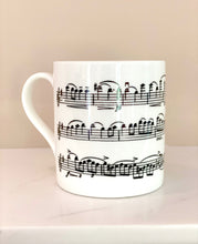 Load image into Gallery viewer, Music gift ideal for classical music fans. Elegant bone china mug with a section of Mendelssohn's Violin Concerto printed on in black. This fabulous mug is perfect for any violin player or music lover. A combination of a full capacity of 310ml and a subtle lip and classic handle design makes this mug both comfortable and stylish. Microwave and dishwasher safe. Height 85mm; Diameter 77mm. View from left thechord.co.uk
