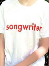 Load image into Gallery viewer, White T-shirt with &quot;songwriter&quot; in red text outlined in black. Shown on model - close up view.