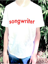 Load image into Gallery viewer, White T-shirt with &quot;songwriter&quot; in red text outlined in black. Shown on model outside.